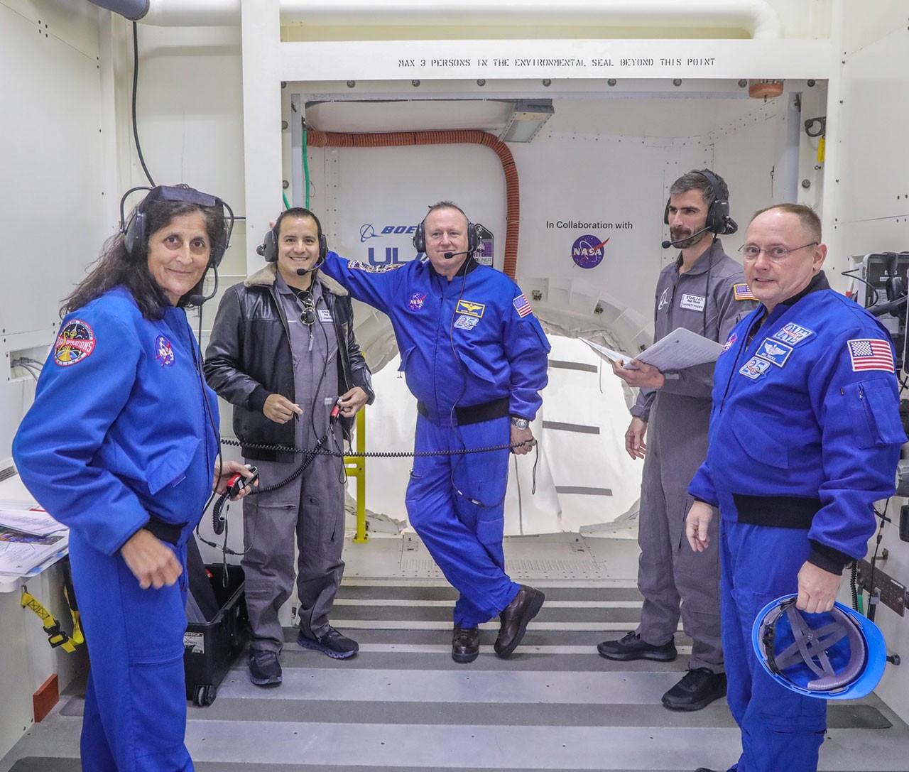 NASA astronauts (in blue) Suni Williams (from left), Butch Wilmore and Mike Fincke, with Starliner Pad Team members Armando Loli (second from left) and Garrett Pinder in the White Room during an Integrated Crew Exercise.