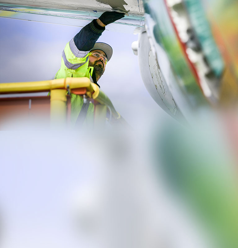 Worker in bucket lift wiping down plane exterior.