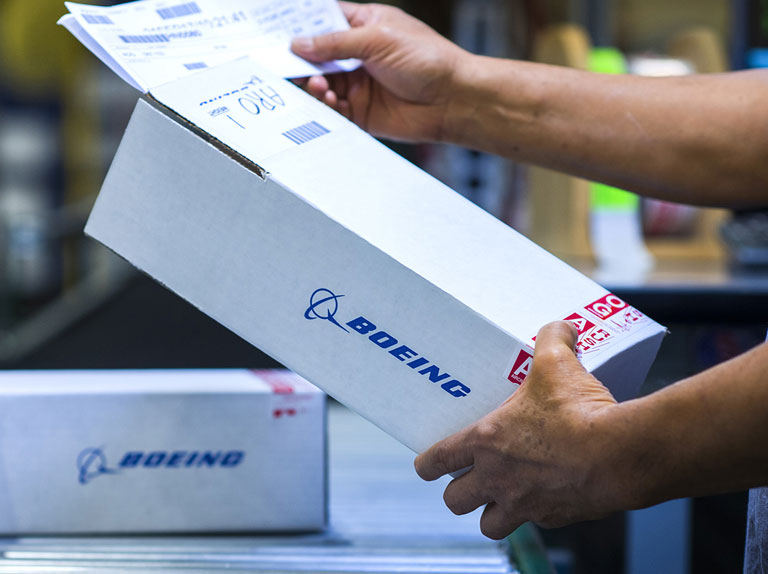 Employee handling a box of parts on a conveyer belt