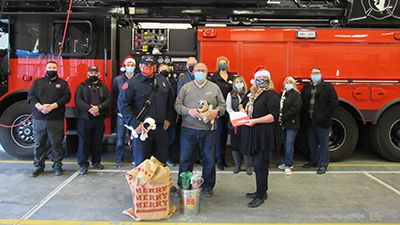 Individuals in front of fire truck with santa kit donation