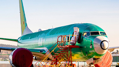 A Boeing 737 aircraft is on a tarmac, showcasing its fuselage before painting, with maintenance equipment nearby.