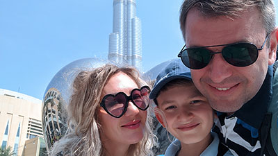 Tatiana Agapova and family poses for a selfie in front of a modern architectural structure.