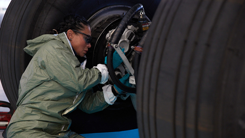 An employee does maintenance on a landing gear assembly.