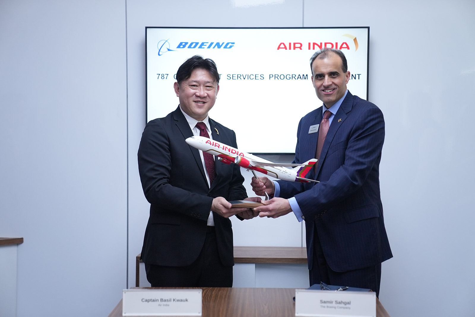 Two male executives from Boeing and Air India pose with an Air India 787 model.
