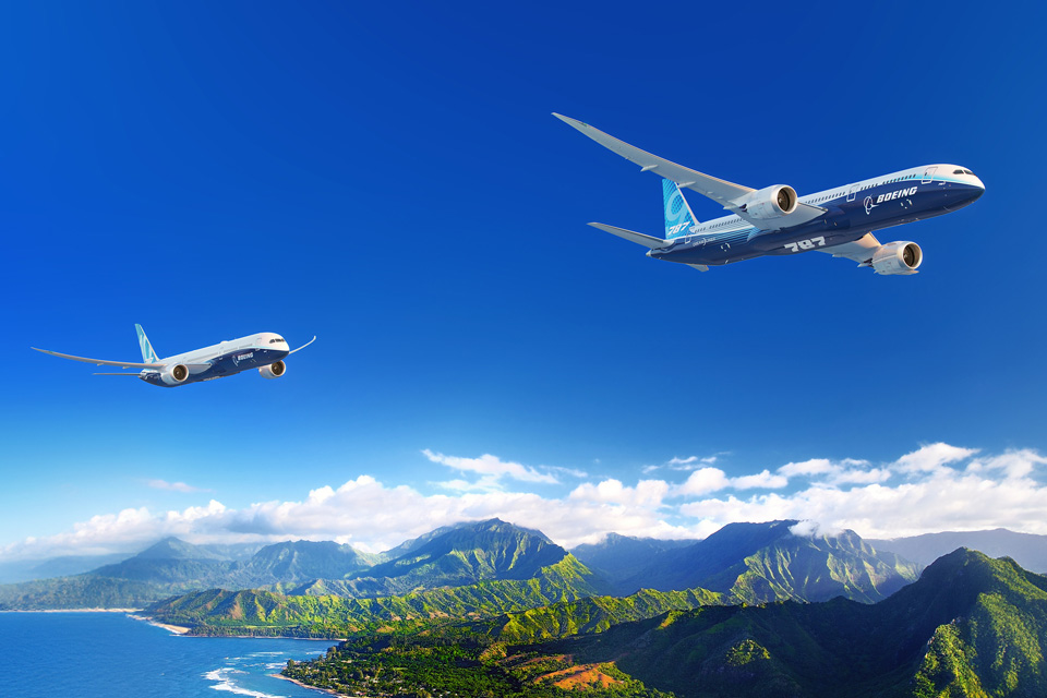 Two 787s flying over tropical mountains and ocean.
