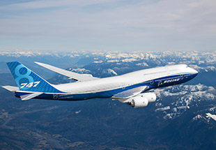 A Boeing 747-8 flying over snow-capped mountains, showcasing its iconic design and blue livery against a clear sky.