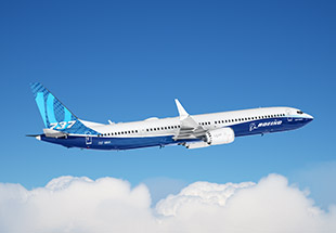 A Boeing 737 soaring through a clear blue sky, with fluffy clouds below.