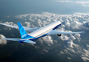 777X in flight over clouds and mountains.