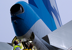 Technicians inspecting the tail section of a Boeing aircraft.