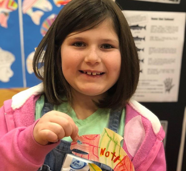 Girl holding paper badge.