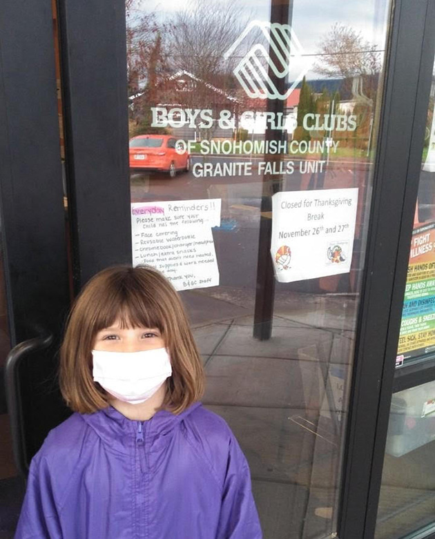 Child weraing mask in front of Boys & Girls Club.