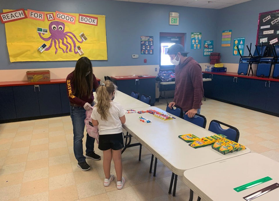 Volunteers help an early learner get ready for the school year.