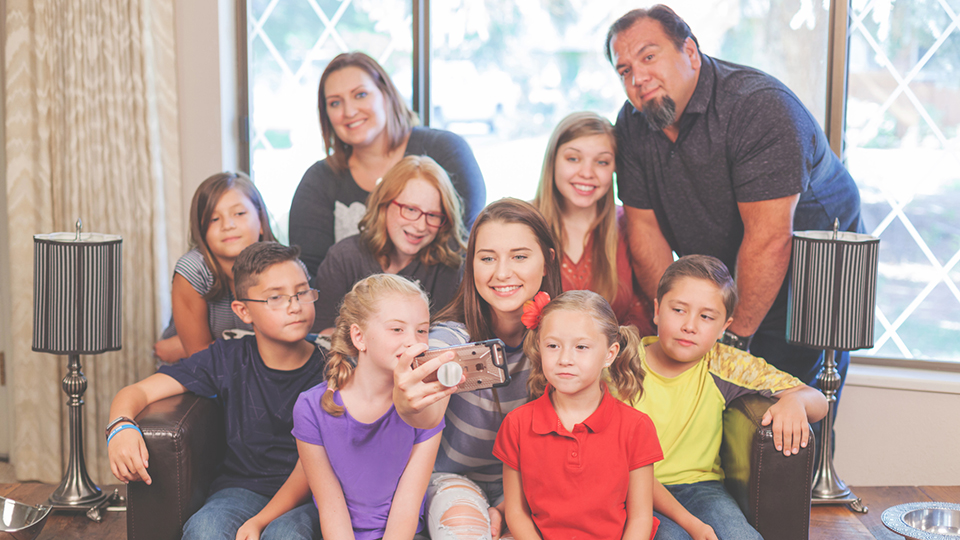 Large group of adults, teens and children in living room Selfie smart phone camera photos