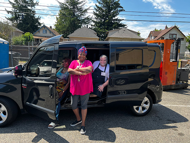 Three people standing in front of a delivery van