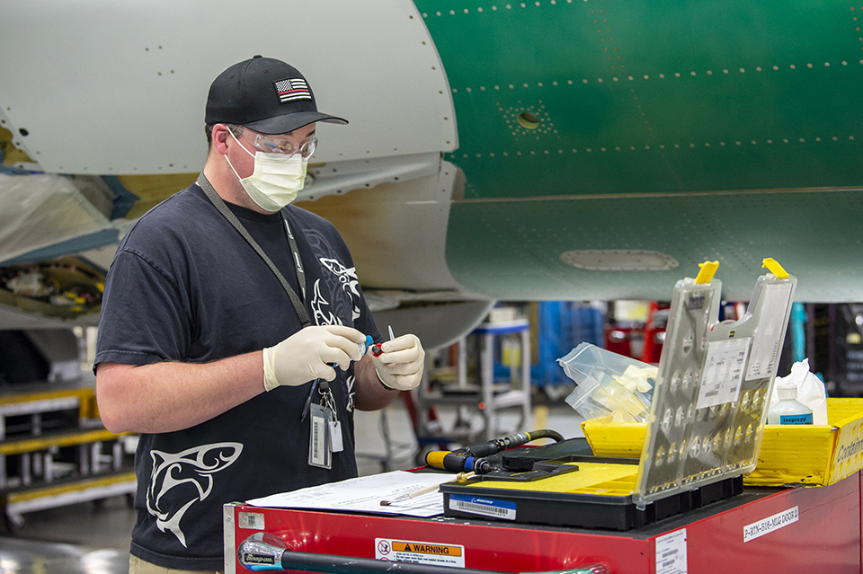 Boeing has implemented several changes at its sites to reduce the risk of COVID-19 in the workplace. Here, an employee in Renton, Washington, wears a mask and puts on gloves to handle tools.