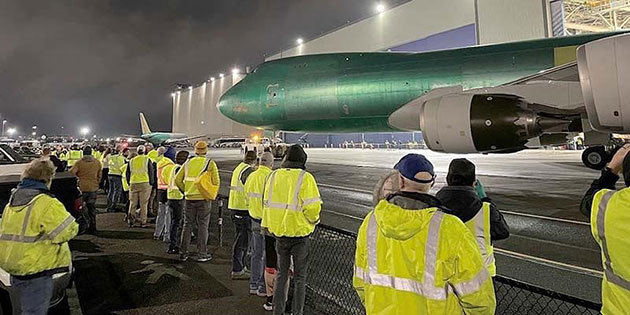   Employees look on as the final 747 rolls out of the factory.