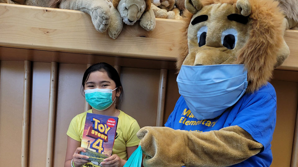 Lion mascot next to child holding book