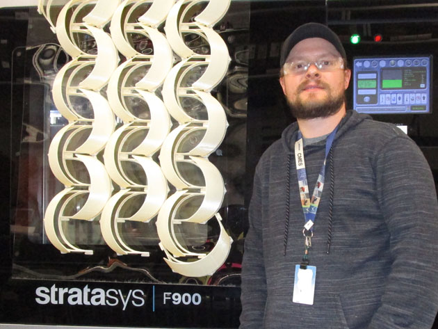 Josh Dunn standing in front of a 3D printer.
