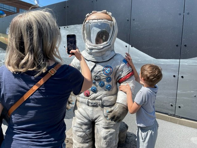  Sara Olson takes a photo of her daughter inside astronaut replica at park grand opening, May 20 (Boeing photo)