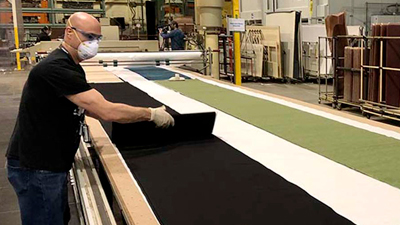 Josh Mattos at Boeing Fabrication’s Interiors Responsibility Center in Everett lay out fabric to be cut into rectangles for cloth face coverings.