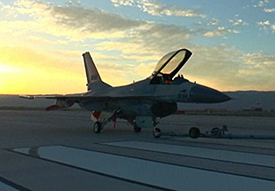 Picture of QF-16 on runway at sunrise.