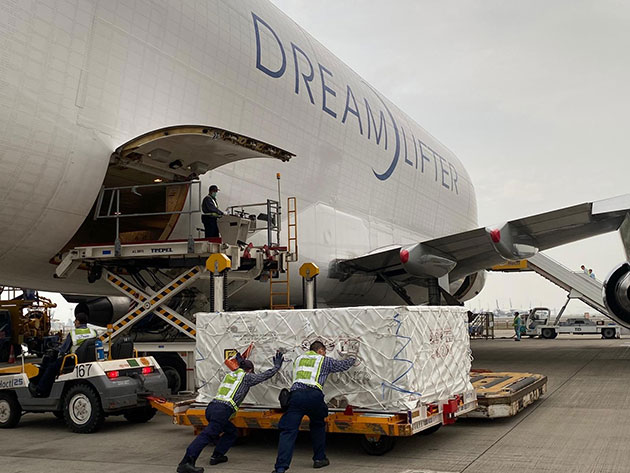 Ground crew pushes pallet of medical equipment toward Dreamlifter cargo door