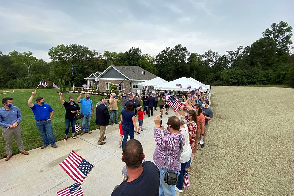 Volunteers waive flags to welcome the Shumaker family 