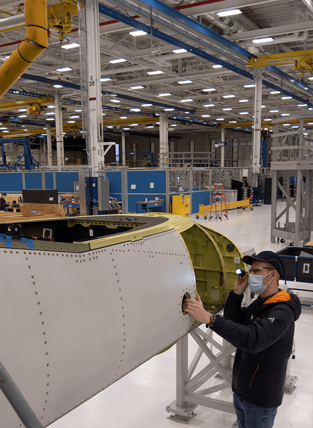 Boeing T-7A Red Hawk flight test engineer Jordan Becker examines the skin of a new eT-7A Red Hawk as it begins its journey through the St. Louis, Missouri production line.