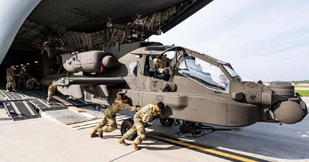 An Apache AH-64E Version 6 Apache helicopter is rolled off an Air Force C-17 in South Korea.