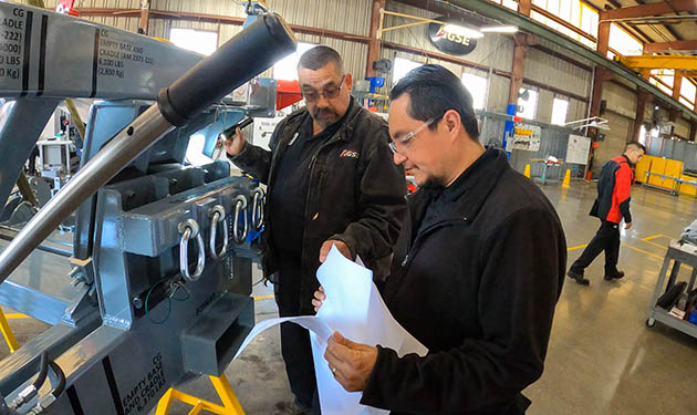   Research & development project engineer Manuel Macias confers with planning manager Elvis Gonzalez while inspecting a KC-46 engine stand.