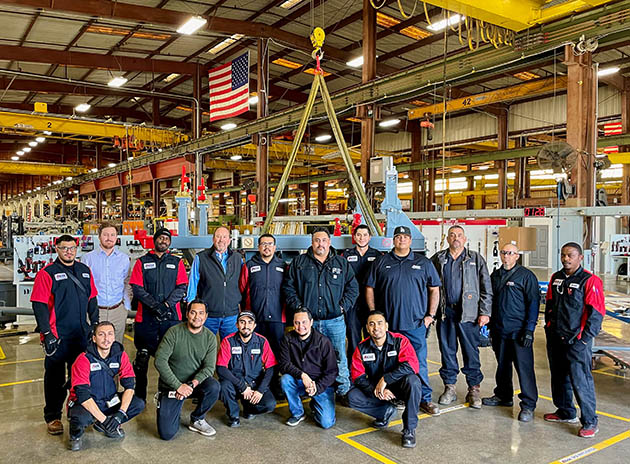AGSE employees pose in front of an engine stand being manufactured for the KC-46A Pegasus.