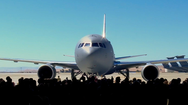 A crowd greets the first KC-46A delivered to Travis Air Force Base as it parks in front of a newly constructed three-bay hangar.