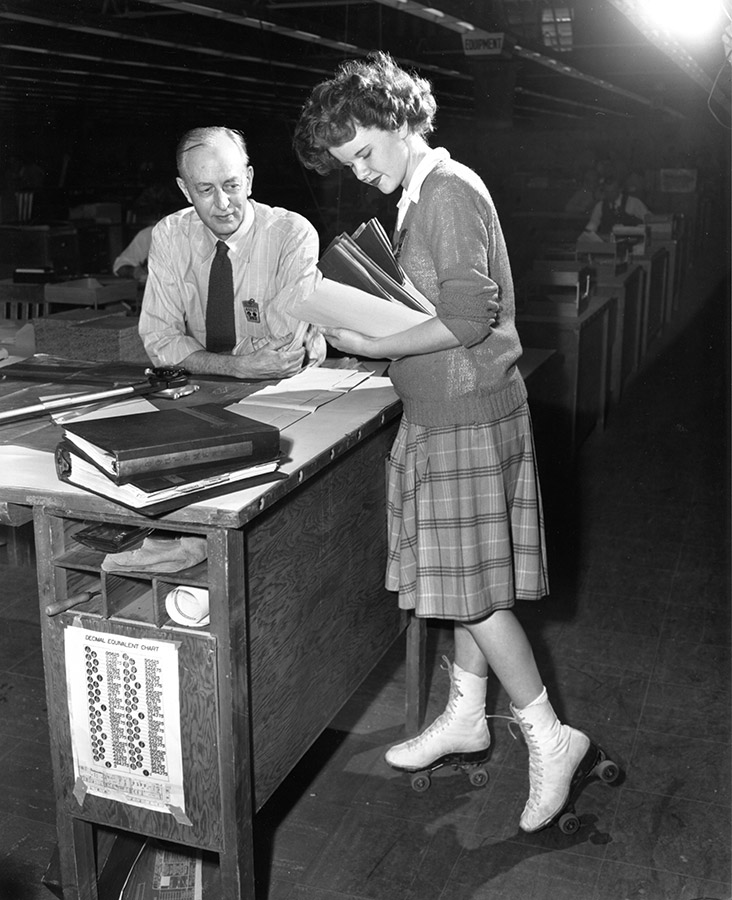 Black and white photo of woman on roller skates delivering mail.