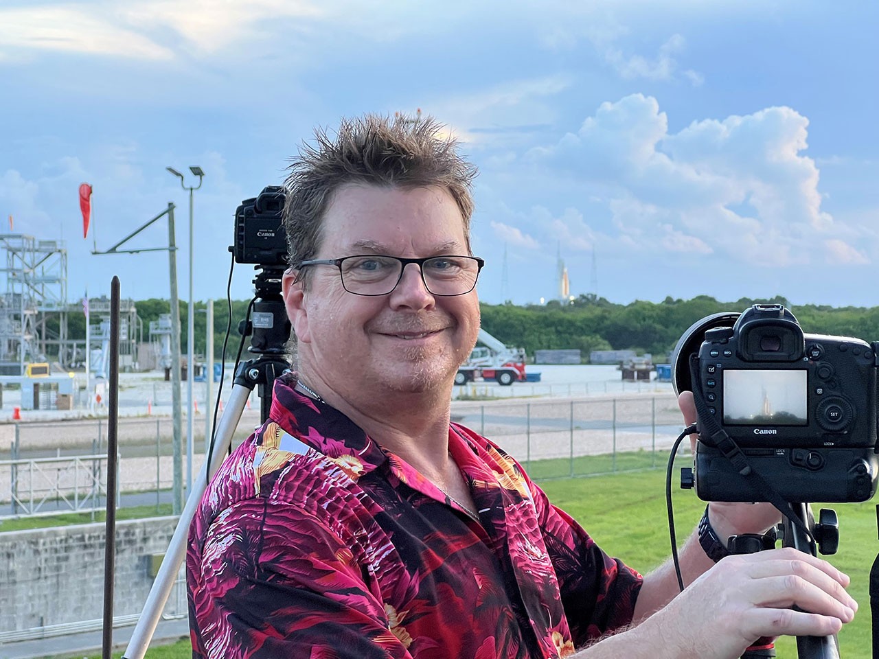 John Grant with the Space Launch System (SLS) rocket in camera view finder and in background on NASA Launch Pad 39B at Kennedy Space Center.