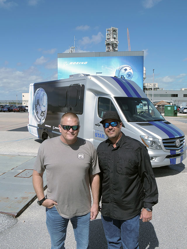 Rodney Perry and Blake Poston, right, in front of the Starliner Astrovan outside the Commercial Crew and Cargo Processing Facility.