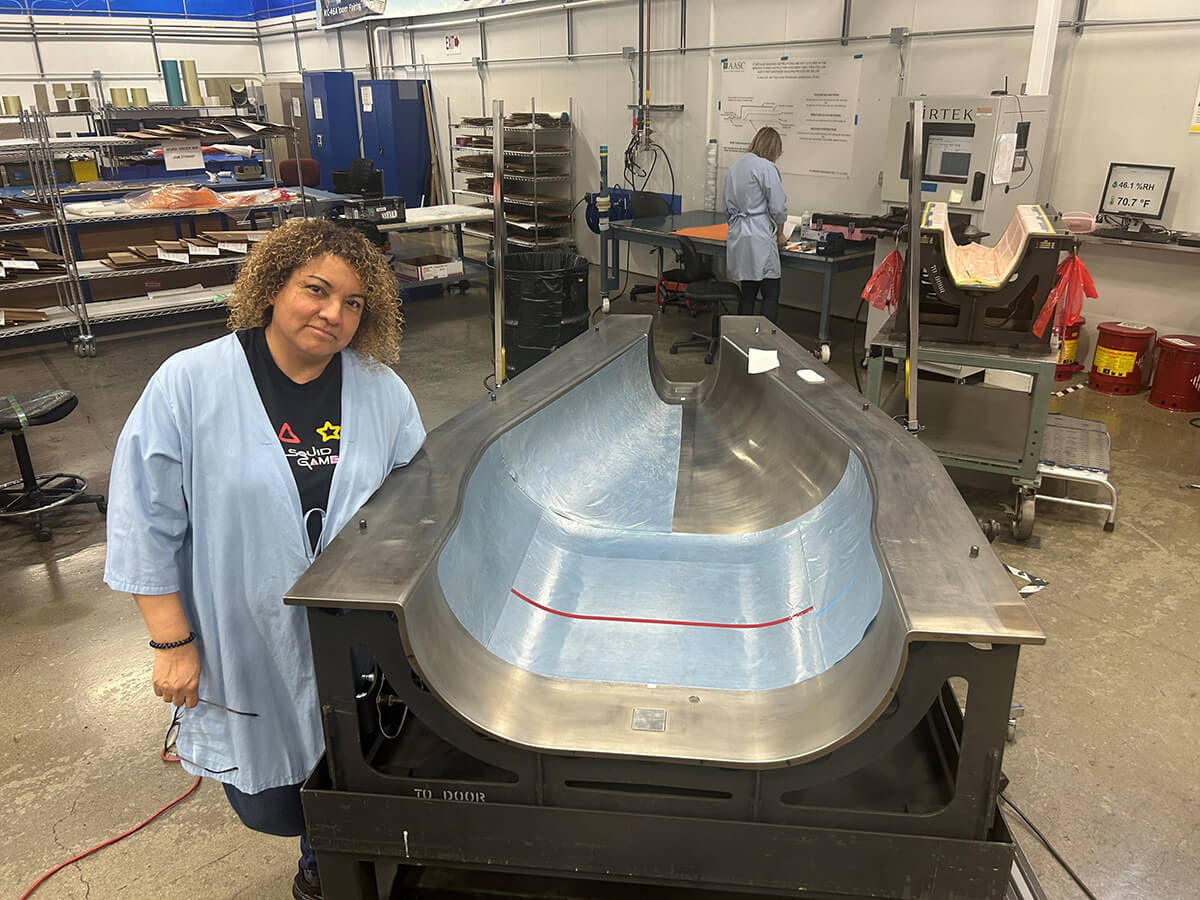 AASC layup technician Juana Saucedo poses with a fairing manufactured for the KC-46A’s refueling boom.