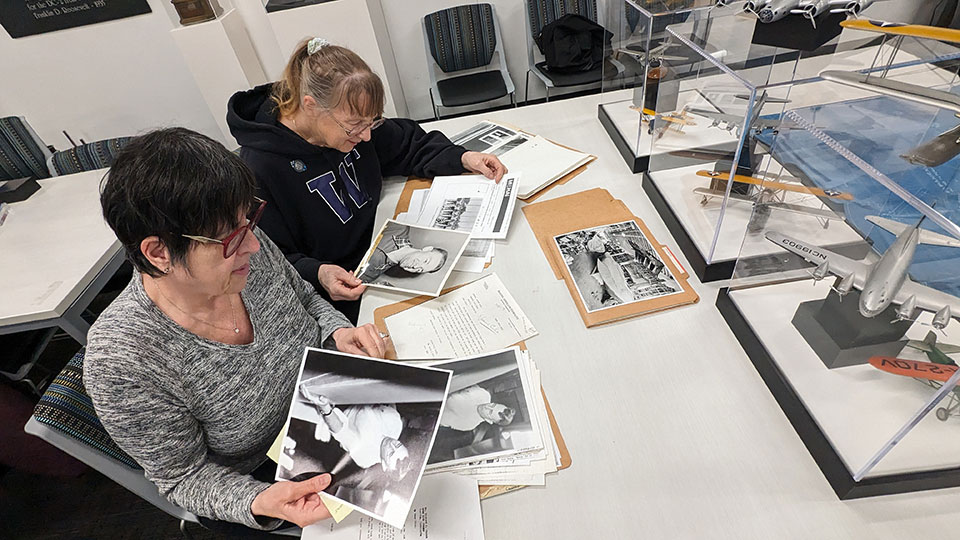 From left: Katie Kusske, granddaughter of George Pocock, and Judy Rantz Willman, daughter of Joe Rantz, review family mementos at the Boeing Archives.