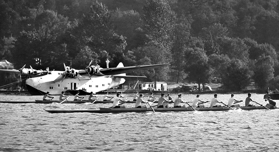 University of Washington rowing shells pass a Boeing 314 Clipper Flying Boat on Lake Washington in Seattle