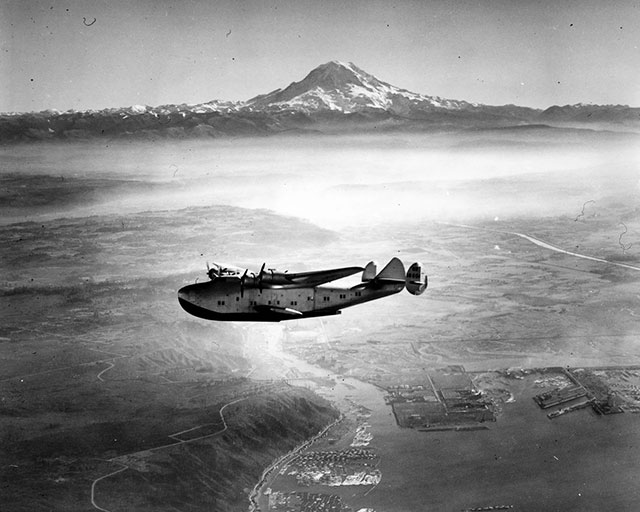 1938: The tradition continued with the Boeing Model 314 Clipper flying over the Port of Tacoma with our old friend saying ‘hello’ in the background. Boeing built 12 Clippers between 1938 and 1941, and no surviving examples exist.