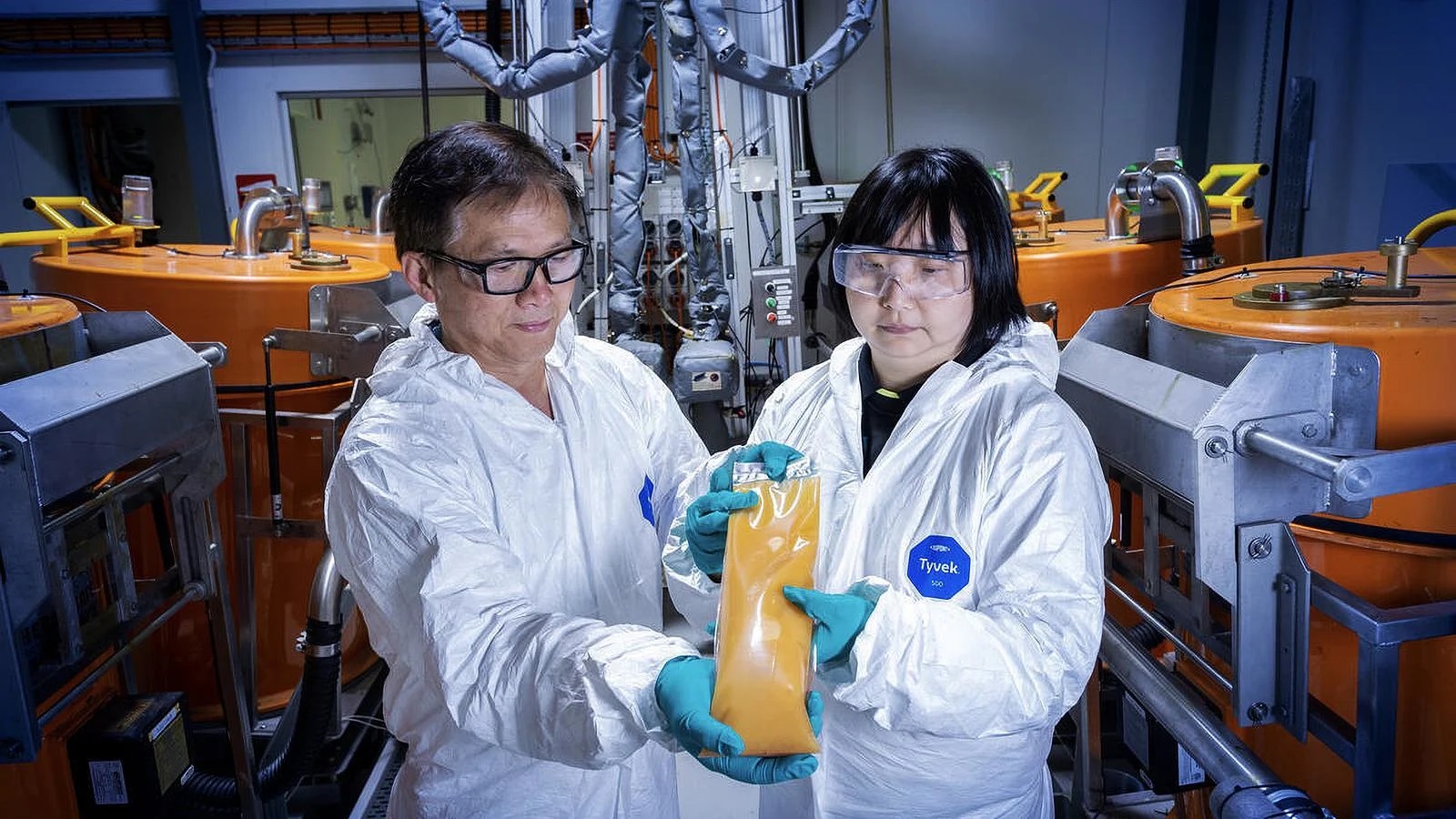 Boeing engineer Andrew Dinh (left) and Tian visually inspect a batch of resin from the new automated two-part mixing system