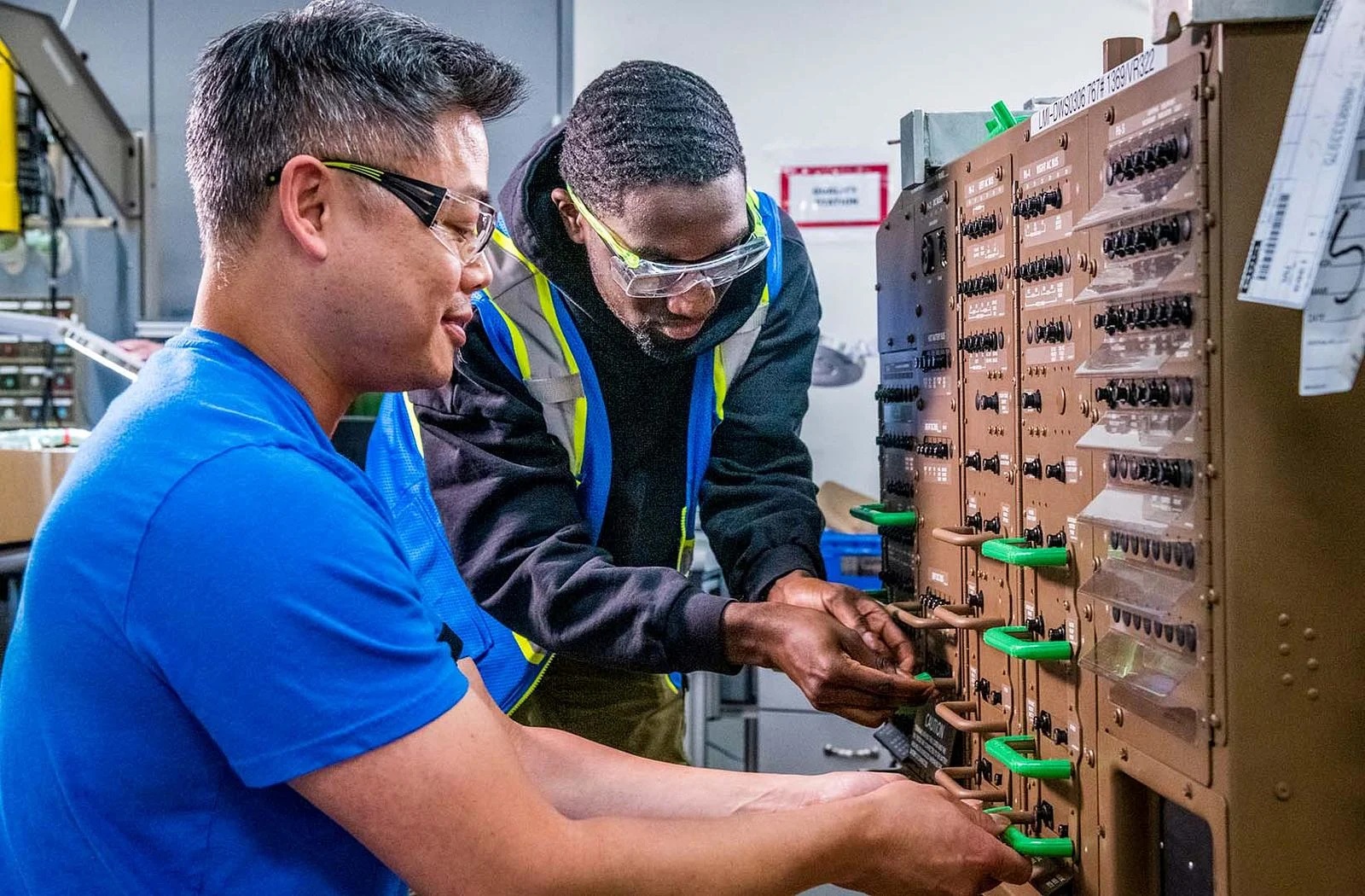 Alex Tran (left) and Curtis Rodriguez Quamina add 3D-printed handle covers to protect the handles during wire installation.