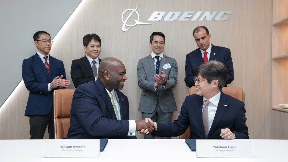 Boeing executive and ANA executive shake hands while other leaders stand behind them.