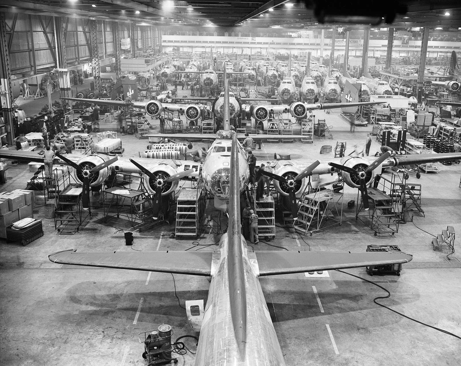 A black and white photo of dozens of B-17 Flying Fortresses lined up for production inside a factory
