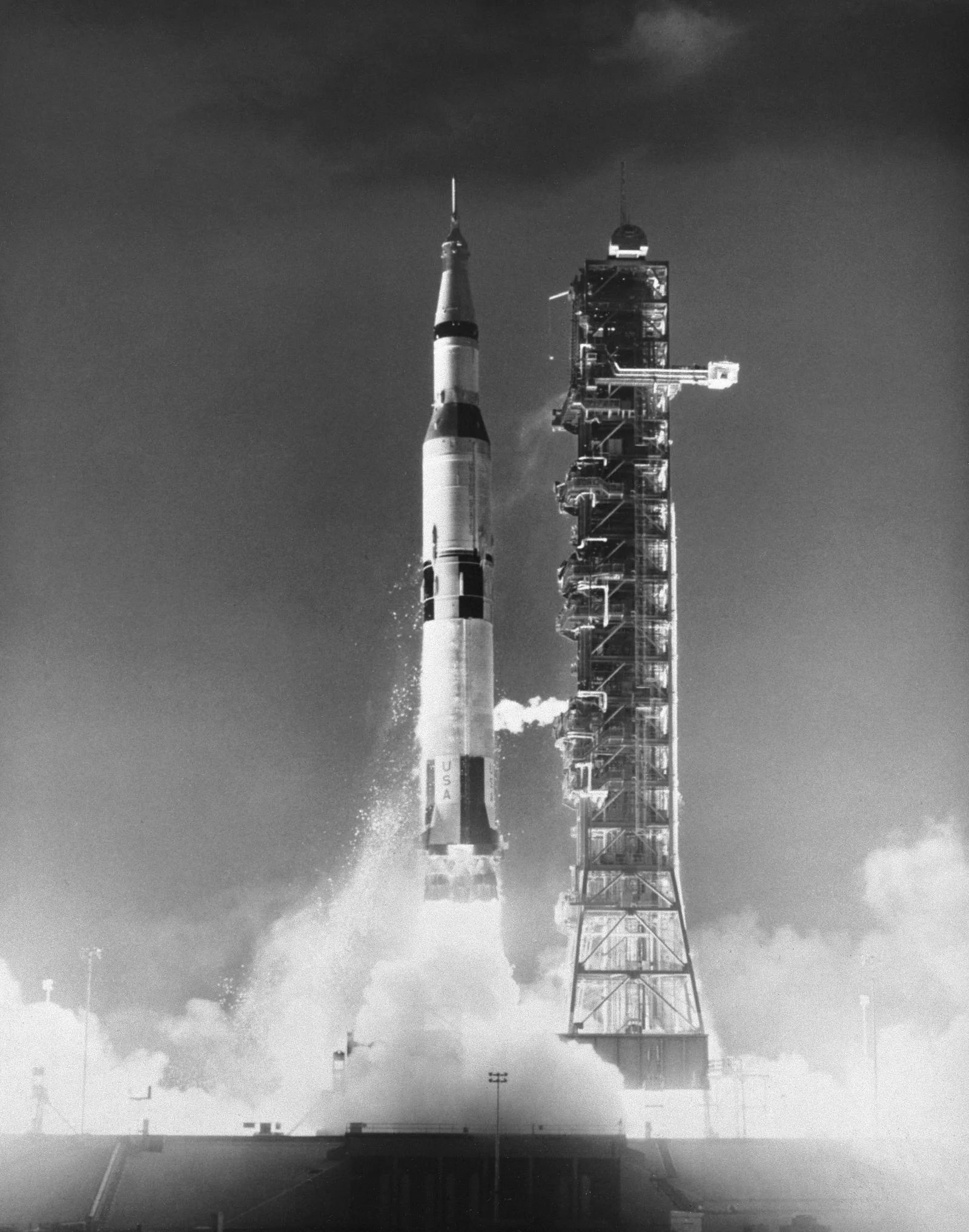 A black and white photo of the Saturn V rocket taking off.