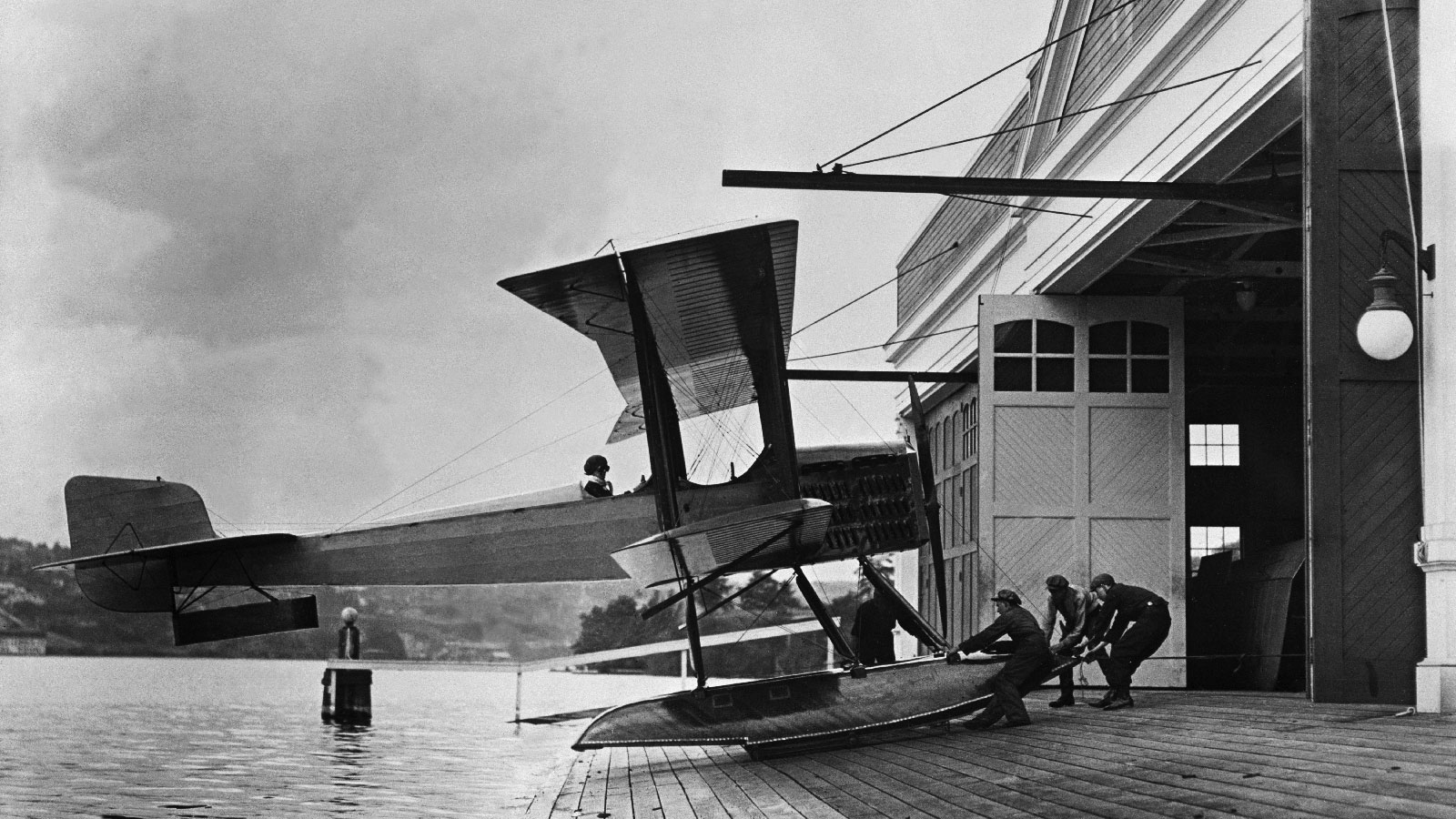 Black and white photo of B&W airplane being pulled onto ramp from water.