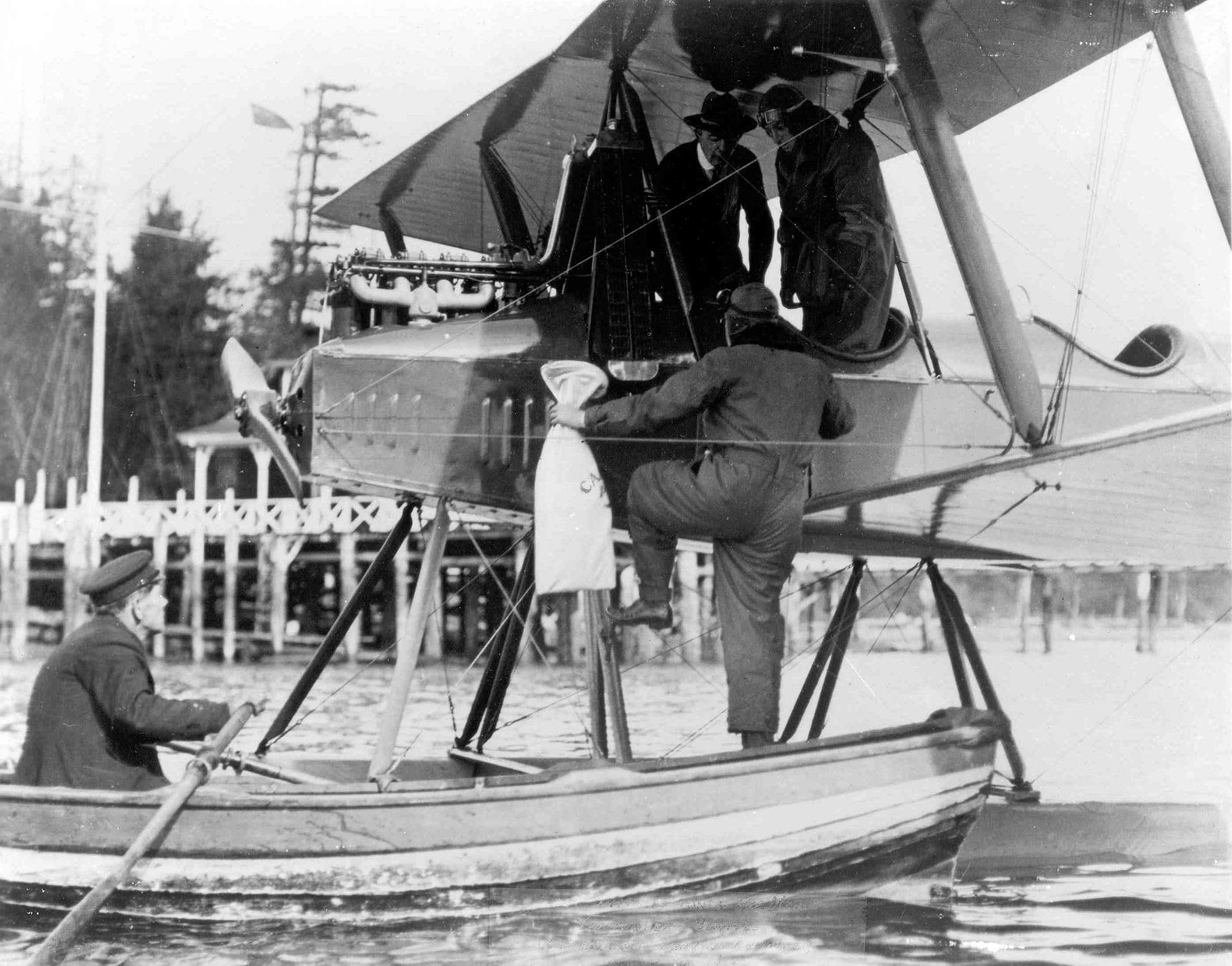 black and white image of two men getting into Model C aircraft with air mail bags