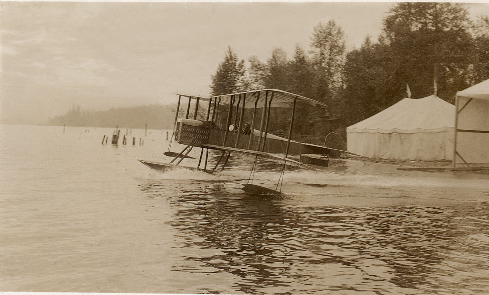 black and white or sepia photo of Bill Boeing flying vintage aircraft on water