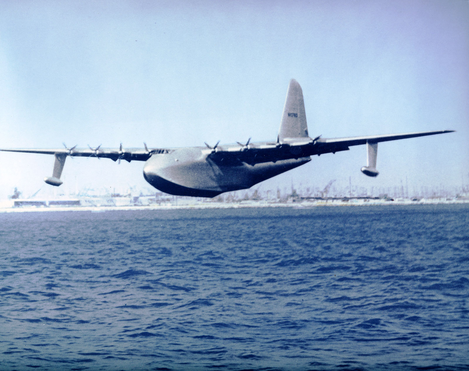 Color photo of the Spruce Goose flying low over the sea. 