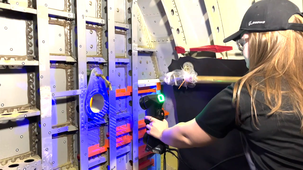 An engineer sweeps a handheld 3D scanner across the fuel bladder of a B-52 aircraft to evaluate 3D-printed parts.