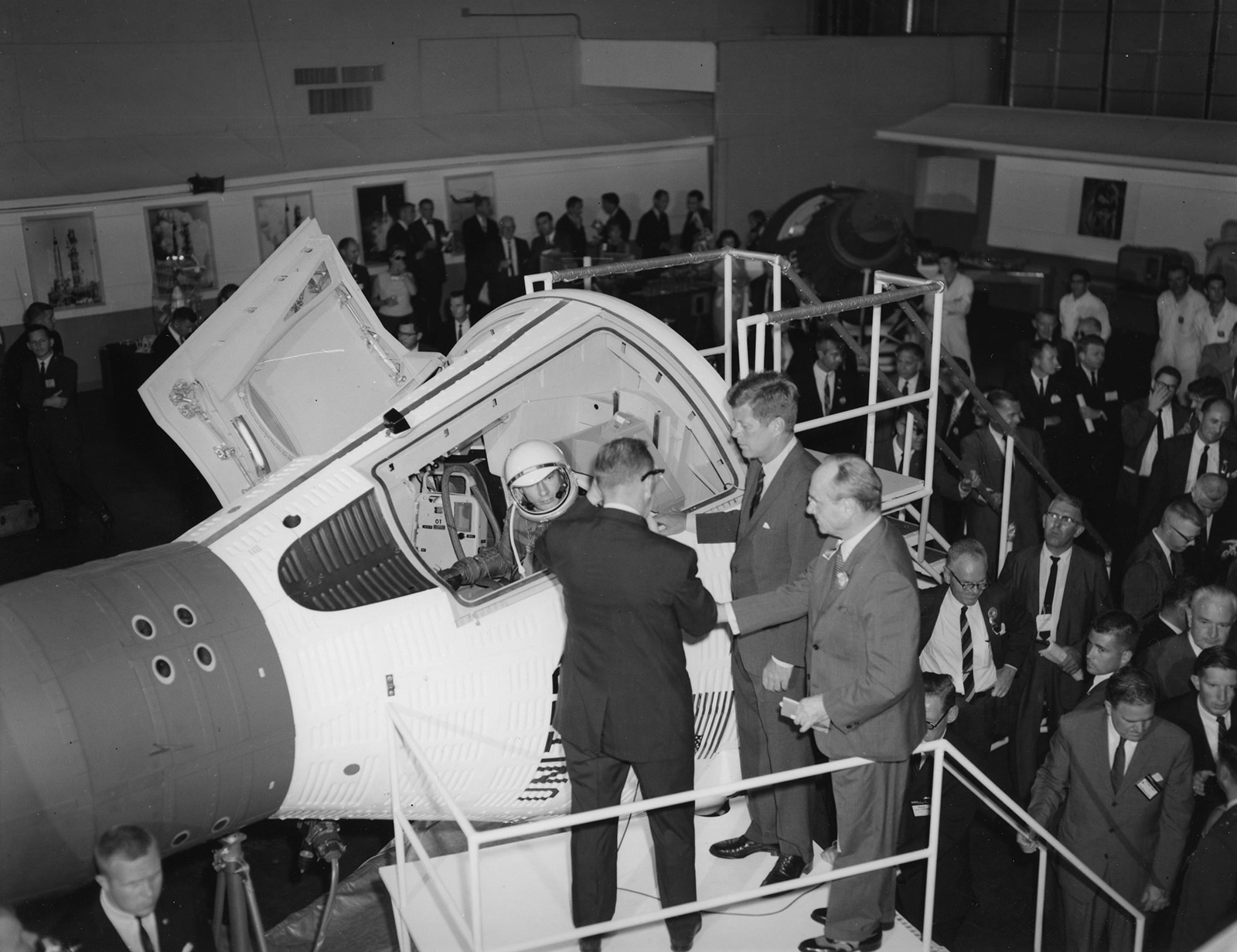 Black and white photo of former president John F. Kennedy viewing an early space craft